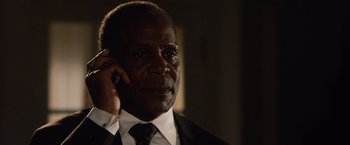 Movie still from “2012” (2009), directed by Roland Emmerich – A man in a suit and tie talking on a cell phone; Close Up shot, Low angle
