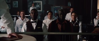 Movie still from “2012” (2009), directed by Roland Emmerich – A group of men standing next to each other in front of a mirror; Medium shot, Over the shoulder angle