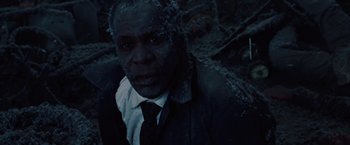 Movie still from “2012” (2009), directed by Roland Emmerich – A man in a suit and tie standing in the woods; Close Up shot, High angle