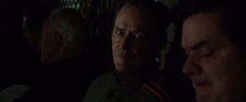 Movie still from “2012” (2009), directed by Roland Emmerich – A person wearing a uniform; Close Up shot, Over the shoulder angle