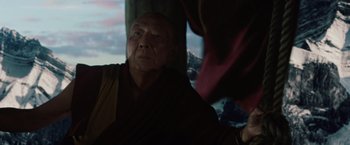 Movie still from “2012” (2009), directed by Roland Emmerich – An older man in a monk's outfit looking out of a window; Close Up shot, Low angle