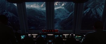 Movie still from “2012” (2009), directed by Roland Emmerich – A group of people sitting in front of a large screen; Extreme Wide shot, High angle