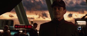 Movie still from “2012” (2009), directed by Roland Emmerich – A man in a military uniform standing in front of an airplane; Close Up shot, Over the shoulder angle