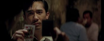 Movie still from “2046” (2004), directed by Kar-Wai Wong – A man holding up a playing card in front of a mirror; Close Up shot, Over the shoulder angle