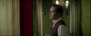 Movie still from “2046” (2004), directed by Kar-Wai Wong – A man standing in front of a window looking to his left; Medium shot, Over the shoulder angle