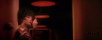 Movie still from “2046” (2004), directed by Kar-Wai Wong – A person smoking a cigarette in front of a red light; Close Up shot, Low angle