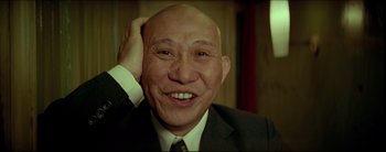 Movie still from “2046” (2004), directed by Kar-Wai Wong – An older man in a suit and tie smiling for the camera; Close Up shot, Low angle