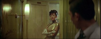 Movie still from “2046” (2004), directed by Kar-Wai Wong – A woman standing in a room with her arms crossed; Medium shot, Over the shoulder angle