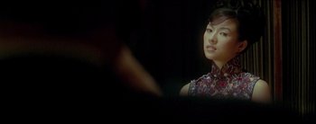 Movie still from “2046” (2004), directed by Kar-Wai Wong – A woman in a red and black dress looking at the camera; Close Up shot, Over the shoulder angle