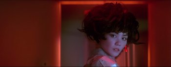 Movie still from “2046” (2004), directed by Kar-Wai Wong – A young woman with short hair is standing in a red room; Close Up shot, Low angle