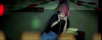 Movie still from “2046” (2004), directed by Kar-Wai Wong – A woman talking on a phone while sitting on a bench; Medium shot, High angle