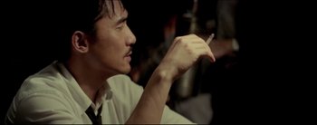 Movie still from “2046” (2004), directed by Kar-Wai Wong – A man holding a cigarette in his right hand; Close Up shot, Over the shoulder angle