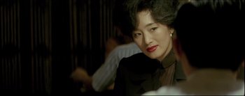 Movie still from “2046” (2004), directed by Kar-Wai Wong – A person wearing a suit and red lipstick; Close Up shot, Over the shoulder angle
