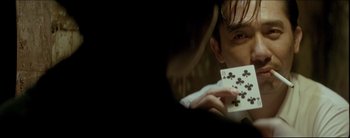 Movie still from “2046” (2004), directed by Kar-Wai Wong – A man holding a deck of playing cards in front of his face; Extreme Close Up shot, Over the shoulder angle