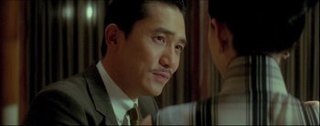 Movie still from “2046” (2004), directed by Kar-Wai Wong – A person wearing a suit and a tie; Close Up shot, Over the shoulder angle
