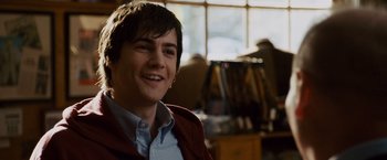 Movie still from “21” (2008), directed by Robert Luketic – A young man smiling for the camera in front of a bookshelf; Close Up shot, Over the shoulder angle