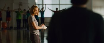 Movie still from “21” (2008), directed by Robert Luketic – A woman holding a video game controller in a room; Medium shot, Over the shoulder angle