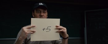 Movie still from “21” (2008), directed by Robert Luketic – A man holding up a sign that says plus five; Close Up shot, Over the shoulder angle