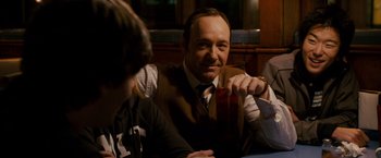 Movie still from “21” (2008), directed by Robert Luketic – A man sitting at a table with two other people; Close Up shot, Over the shoulder angle