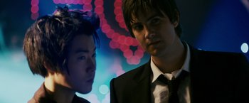 Movie still from “21” (2008), directed by Robert Luketic – Two young men in suits standing in front of lights; Close Up shot, Over the shoulder angle