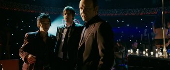 Movie still from “21” (2008), directed by Robert Luketic – A man in a suit and tie standing next to another man in a suit and tie; Medium shot, Low angle