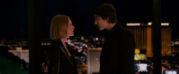 Movie still from “21” (2008), directed by Robert Luketic – A man and a woman standing next to each other in front of a city skyline at night; Medium shot, Over the shoulder angle