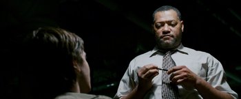 Movie still from “21” (2008), directed by Robert Luketic – A man in a tie is talking to another man in front of a mirror; Medium shot, Over the shoulder angle