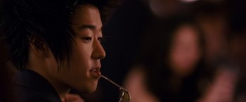 Movie still from “21” (2008), directed by Robert Luketic – A man with a long black hair is holding a pair of eyeglasses in his mouth; Close Up shot, Over the shoulder angle