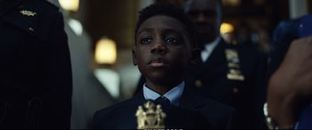 Movie still from “21 Bridges” (2019), directed by Brian Kirk – A young boy in a suit and tie looking up; Close Up shot, Low angle