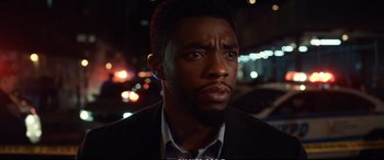 Movie still from “21 Bridges” (2019), directed by Brian Kirk – A person wearing a suit and tie; Close Up shot, Low angle