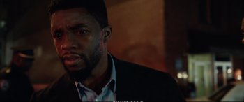 Movie still from “21 Bridges” (2019), directed by Brian Kirk – A person wearing a suit and tie; Close Up shot, Low angle