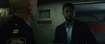 Movie still from “21 Bridges” (2019), directed by Brian Kirk – A man in a suit and tie standing next to another man in a suit; Close Up shot, Low angle
