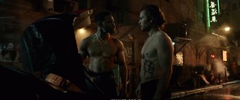 Movie still from “21 Bridges” (2019), directed by Brian Kirk – Two shirtless men standing next to each other in a room; Medium shot, Over the shoulder angle