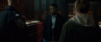 Movie still from “21 Bridges” (2019), directed by Brian Kirk – A man in a suit standing in front of a wine rack; Medium shot, Low angle