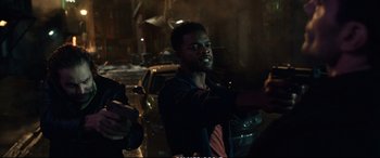 Movie still from “21 Bridges” (2019), directed by Brian Kirk – A man standing in front of a car on a city street; Medium shot, Over the shoulder angle