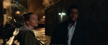 Movie still from “21 Bridges” (2019), directed by Brian Kirk – A man and a woman standing next to each other on a street; Medium shot, Over the shoulder angle