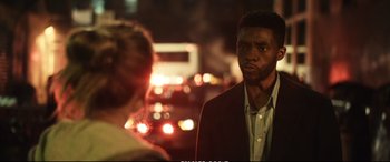Movie still from “21 Bridges” (2019), directed by Brian Kirk – A man standing next to another man on a city street; Close Up shot, Over the shoulder angle