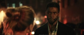 Movie still from “21 Bridges” (2019), directed by Brian Kirk – A man in a suit and tie looking at the camera; Close Up shot, Over the shoulder angle