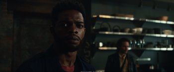 Movie still from “21 Bridges” (2019), directed by Brian Kirk – A man with a beard is standing next to another man; Close Up shot, Over the shoulder angle