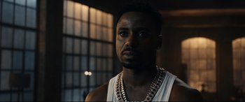 Movie still from “21 Bridges” (2019), directed by Brian Kirk – A person wearing a chain around their neck; Close Up shot, Low angle