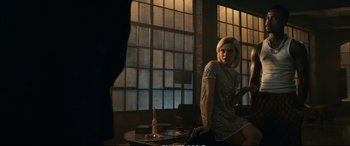 Movie still from “21 Bridges” (2019), directed by Brian Kirk – A woman is sitting on a chair in a room; Medium shot, Over the shoulder angle