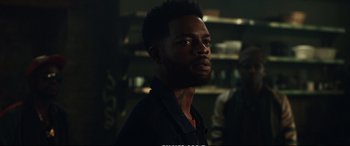 Movie still from “21 Bridges” (2019), directed by Brian Kirk – A man in a black shirt is looking to his left; Close Up shot, Over the shoulder angle