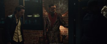 Movie still from “21 Bridges” (2019), directed by Brian Kirk – A man wearing a robe standing in front of a brick wall; Medium shot, Over the shoulder angle