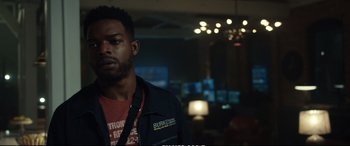 Movie still from “21 Bridges” (2019), directed by Brian Kirk – A man in a black jacket standing in front of a camera; Medium shot, Over the shoulder angle