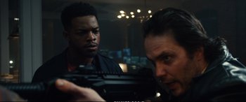 Movie still from “21 Bridges” (2019), directed by Brian Kirk – Two men looking at each other in a dark room; Close Up shot, Over the shoulder angle