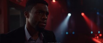 Movie still from “21 Bridges” (2019), directed by Brian Kirk – A man in a suit looking into the distance; Close Up shot, Over the shoulder angle