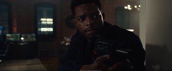 Movie still from “21 Bridges” (2019), directed by Brian Kirk – A man holding a gun while wearing a black shirt; Close Up shot, Over the shoulder angle