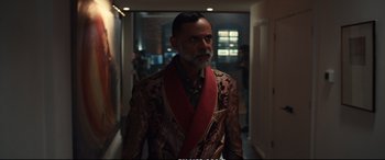 Movie still from “21 Bridges” (2019), directed by Brian Kirk – A man with a beard wearing a suit and a red tie; Medium shot, Over the shoulder angle