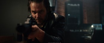 Movie still from “21 Bridges” (2019), directed by Brian Kirk – A man in a black leather jacket holding a gun; Close Up shot, Low angle