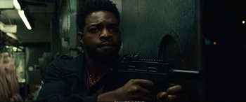 Movie still from “21 Bridges” (2019), directed by Brian Kirk – A man holding a gun in a room with a wall; Close Up shot, Low angle